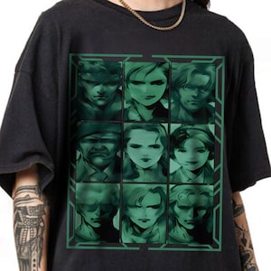 May include: Black t-shirt featuring a grid of nine green-tinted portraits. The portraits have a digital art style. The shirt has a crew neck and short sleeves. A gold chain is visible at the neckline.