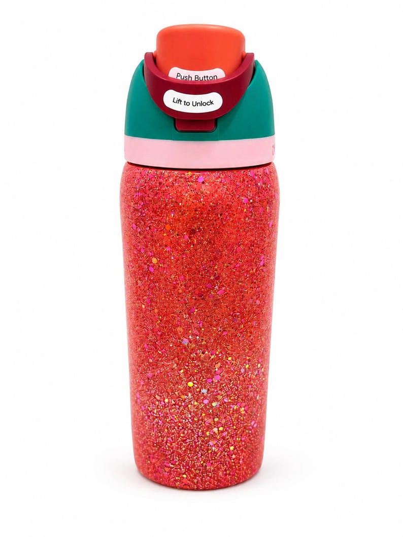 May include: A cylindrical water bottle with a vibrant red glitter finish. The lid features a teal band, a light pink ring, and a red top section. White labels on the lid display the text Push Button and Lift to Unlock in black font.