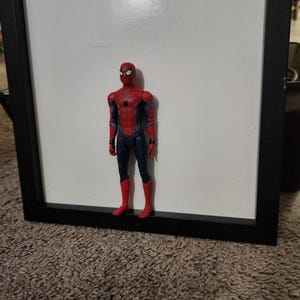 Op de afbeelding: Een Spider-Man actiefiguur, staand voor een witte achtergrond. De figuur is overwegend rood en blauw, met zwarte accenten. Het heeft een gedetailleerd kostuumontwerp en staat rechtop.