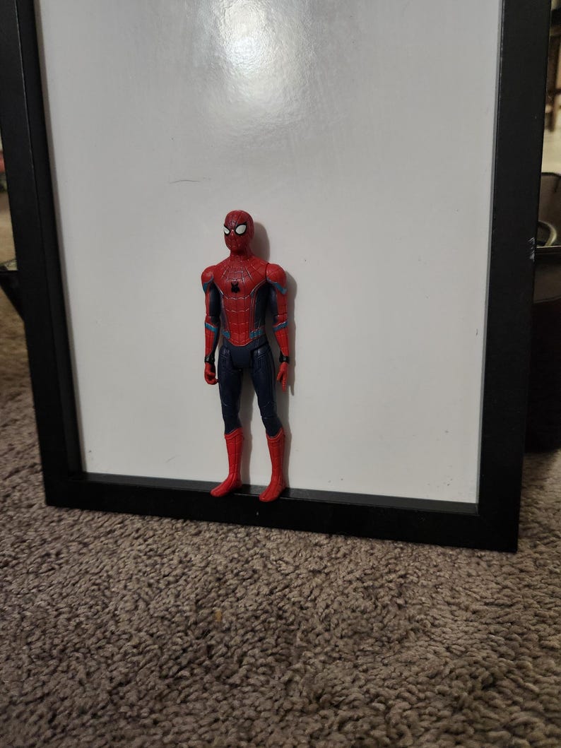 Op de afbeelding: Een Spider-Man actiefiguur, staand voor een witte achtergrond. De figuur is overwegend rood en blauw, met zwarte accenten. Het heeft een gedetailleerd kostuumontwerp en staat rechtop.