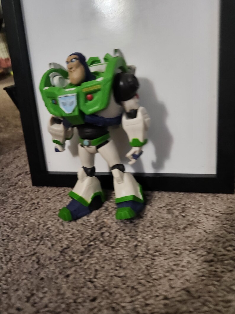 May include: A Buzz Lightyear action figure, featuring a green and white spacesuit with blue and black accents. The figure has a determined expression and is posed in a standing position. The toy is a collectible item.
