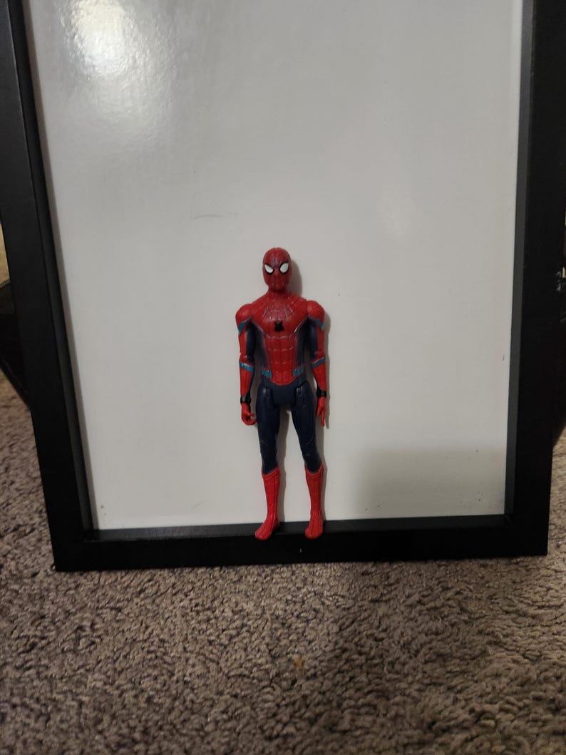 Op de afbeelding: Een rood, blauw en zwart Spider-Man actiefiguur. Het figuur staat voor een witte achtergrond. Het figuur draagt een rood en zwart pak met een spinnenwebontwerp.
