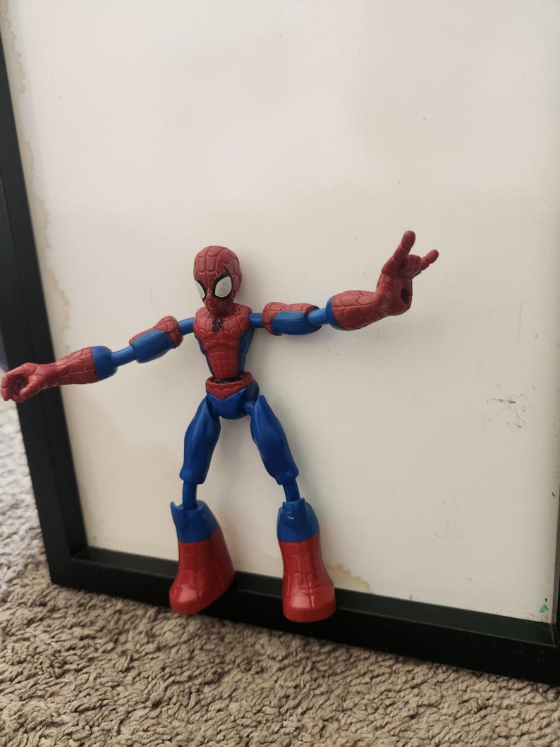 May include: A red and blue Spider-Man action figure with a web pattern on the head and chest. The figure has articulated joints at the shoulders, elbows, hips, and knees, with one hand posed in a web-shooting gesture and the other hand open.