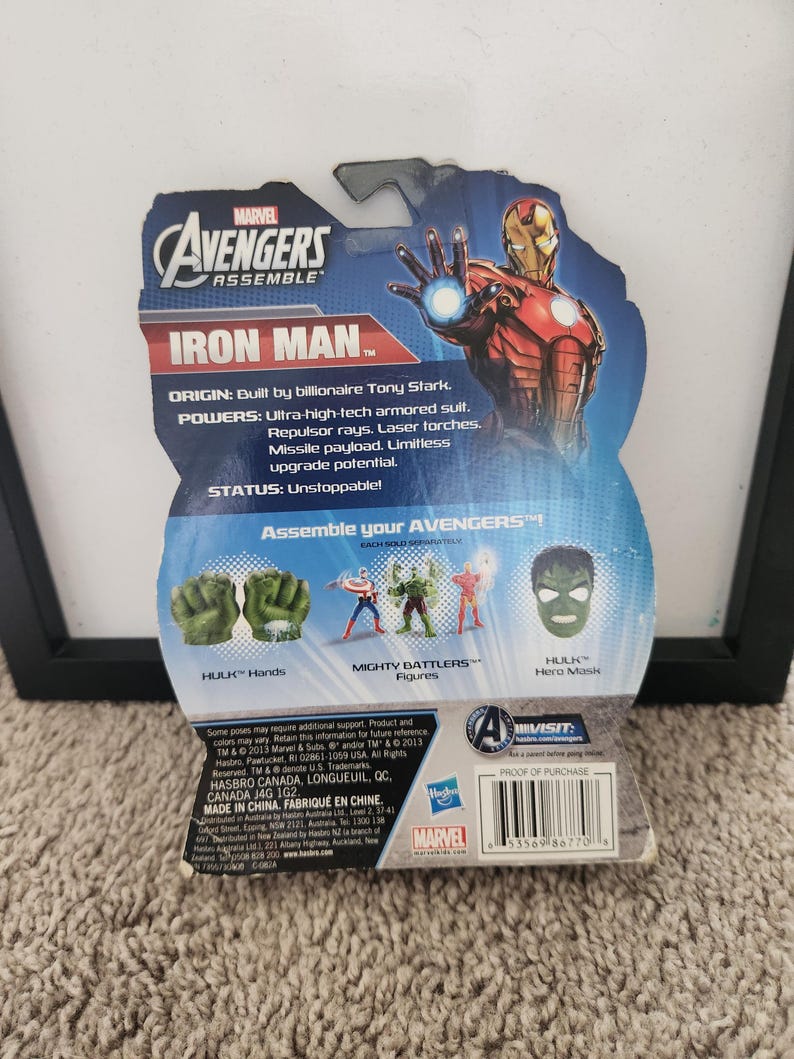May include: A plastic action figure packaging featuring Iron Man from the Marvel Avengers Assemble series. The packaging is blue and red with a picture of Iron Man in his red and gold suit. The back of the packaging shows the different parts of the action figure, including Hulk's hands, Captain America's figure, and Hulk's mask.