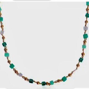 May include: A necklace featuring a delicate gold-toned chain interspersed with small, polished gold-colored spherical beads and various square-shaped beads in shades of light green, teal, and translucent white, arranged in a repeating pattern.