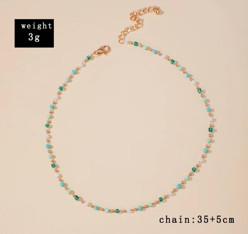 May include: A delicate necklace featuring small gold-tone beads interspersed with tiny square-shaped beads in shades of turquoise, emerald green, and white. The necklace includes a lobster clasp and an extender chain. Text states weight 3g and chain 35+5cm.
