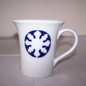 May include: White ceramic mug with a blue snowflake design.