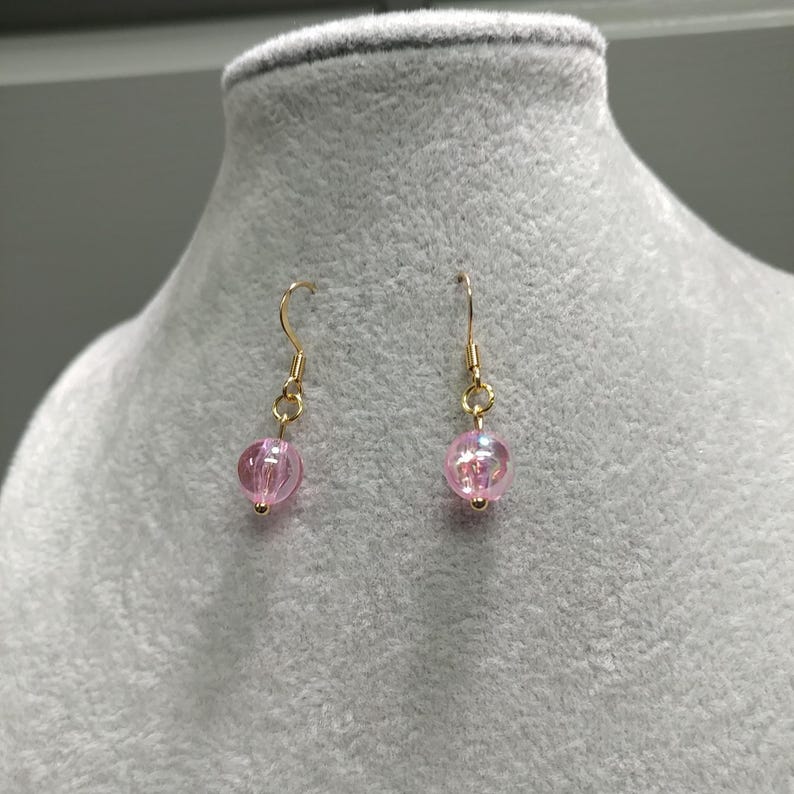 May include: A pair of gold dangle earrings with pink iridescent glass beads.