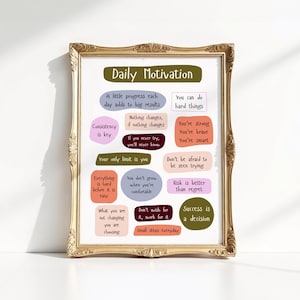 May include: A framed print with a gold ornate frame. The print features the words "Daily Motivation" at the top, with various motivational quotes in colorful bubble shapes. The quotes include "Consistency is key" and "Success is a decision."
