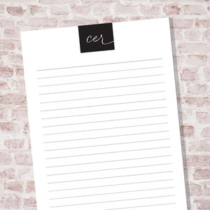 May include: A white lined notepad with a black square at the top that says "cer" in white cursive writing.