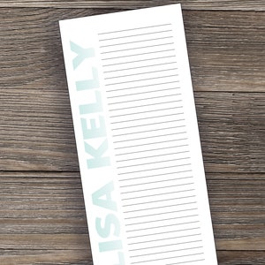 May include: A white lined notepad with the name "LISA KELLY" printed in a light blue gradient on the left side.