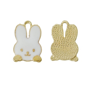 May include: Two gold-coloured bunny charms. One charm is white with a gold outline and the other is gold with a textured surface.