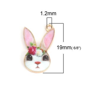 K&ouml;nnte beinhalten: Goldfarbener Metall-Anh&auml;nger mit einem wei&szlig;en Hasen mit rosa Ohren und einem Blumenkranz. Der Anh&auml;nger ist 19 mm (6/8 Zoll) hoch und 12 mm breit.