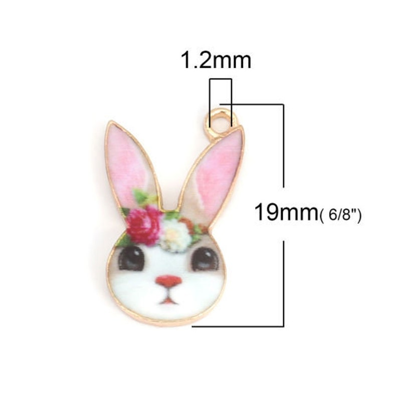 K&ouml;nnte beinhalten: Goldfarbener Metall-Anh&auml;nger mit einem wei&szlig;en Hasen mit rosa Ohren und einem Blumenkranz. Der Anh&auml;nger ist 19 mm (6/8 Zoll) hoch und 12 mm breit.