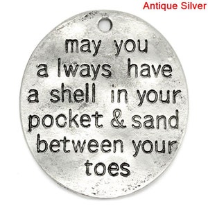 May include: Antique silver charm with the text "may you always have a shell in your pocket & sand between your toes".