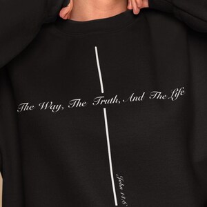 Puede incluir: Sudadera negra con una cruz blanca y el texto "The Way, The Truth, And The Life" con la referencia bíblica "John 14:6".