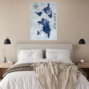 Può includere: Una stampa di mappa del mondo blu navy con una rosa dei venti in alto a sinistra e la scritta "NAVY MAP" in verticale a destra. La mappa è su uno sfondo azzurro chiaro e strutturato. La stampa è sopra un letto.