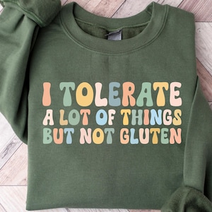 K&ouml;nnte beinhalten: Ein gr&uuml;ner Pullover mit dem Text "I tolerate a lot of things but not gluten" in bunten Retro-Lettern.