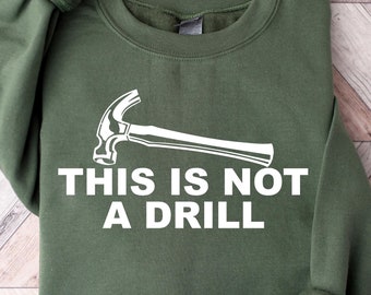 Op de afbeelding: Een groen sweatshirt met een witte hamer afbeelding en de tekst "Dit is geen oefening".
