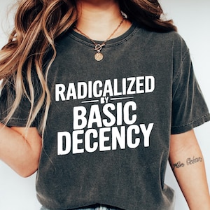 Pode incluir: Uma camiseta cinza escura com o texto "Radicalized by Basic Decency" impresso em branco.