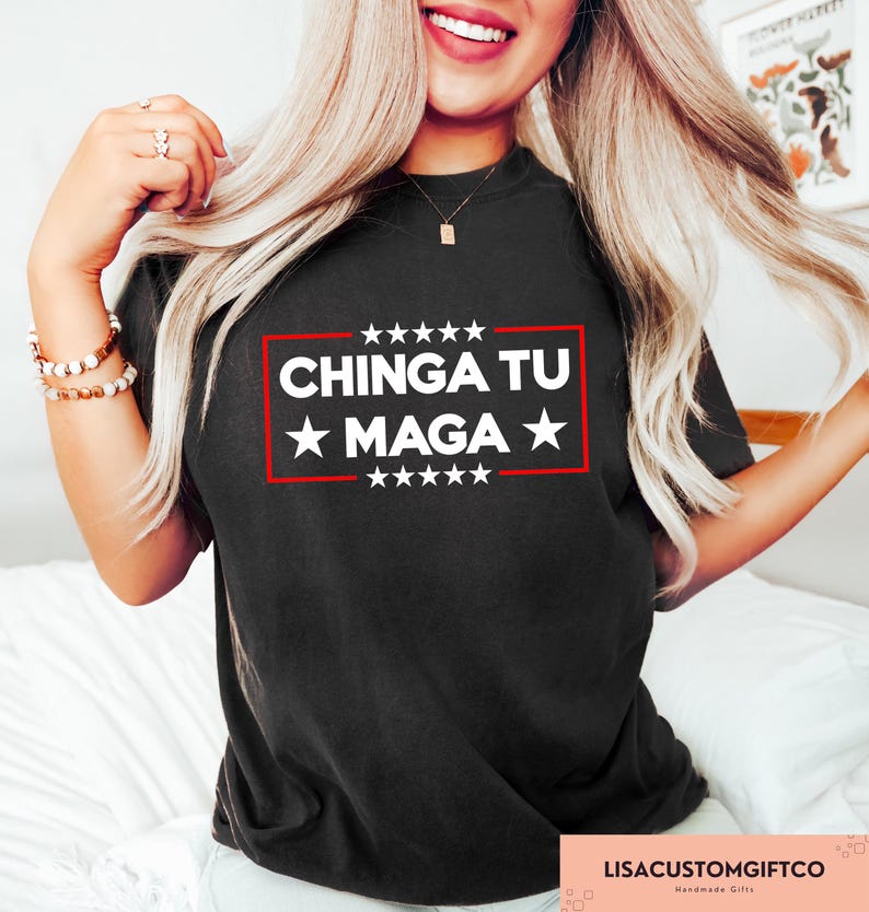 May include: Black t-shirt featuring the text "CHINGA TU MAGA" in white, within a red rectangle and white stars. The shirt has a crew neck design.