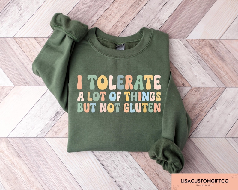 K&ouml;nnte beinhalten: Ein gr&uuml;ner Pullover mit dem Text "I tolerate a lot of things but not gluten" in bunten Retro-Lettern.