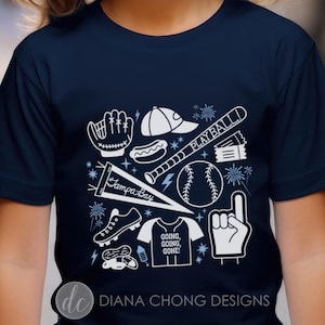 Pode incluir: Camiseta azul marinho com um design branco com tema de beisebol. O design inclui uma bola de beisebol, um bastão, uma luva, uma flâmula e as palavras "PLAY BALL!" e "GOING, GOING, GONE!". Também apresenta um boné de beisebol, um cachorro-quente e um dedo de espuma.