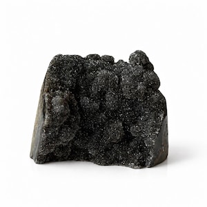 May include: A dark black mineral specimen featuring a rough, crystalline, and textured surface with a sparkling appearance. The stone has an irregular, jagged shape with a dense cluster of small, reflective crystals covering the front face.