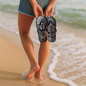 May include: A pair of black flip-flops with a white and gray patterned design. The flip-flops have the text "NGARU" printed on the straps.