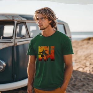 May include: A green t-shirt with a graphic print of a stylized eye with flames behind it. The graphic is in a square shape and the text "KHI" is visible within the graphic.