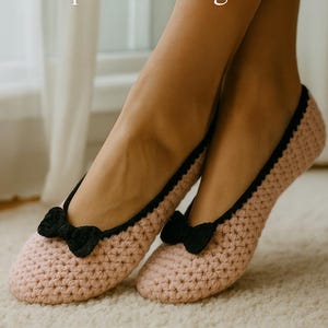 May include: A pair of light pink crocheted slippers with black trim and a black bow on the toe. The image includes the text "Let your yarn dance to the rhythm of quiet mornings." and the website address www.crochix.com.