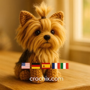 Peut inclure: Un chien Yorkshire Terrier crocheté avec une fourrure marron et beige, assis sur une surface en bois. Le chien a de grands yeux sombres et un petit nez noir. L'adresse du site Web crochix.com est visible en bas de l'image.