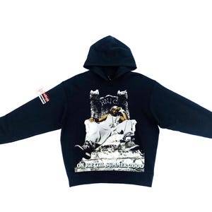 May include: Black hooded sweatshirt featuring a graphic of a person on a throne. The graphic includes the text "HNIC" and "ON ICE TIL SUMMER 2000". The sweatshirt has a hood and long sleeves.