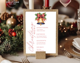 May include: A gold glitter-framed Christmas menu card with a watercolor bell illustration. The menu lists appetizers, entrees, desserts, and drinks. The text "Christmas Menu" is written in red script. The card is displayed on a table setting.