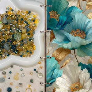 May include: A white star-shaped dish filled with gold, yellow, and teal beads and gems. Next to it is a floral design with large teal and white flowers and gold accents. The image is split by a binder.