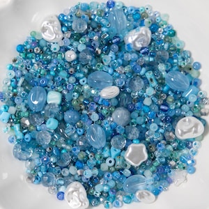 Puede incluir: Un gran surtido de cuentas de vidrio azules y blancas en varias formas y tamaños. Las cuentas son perfectas para hacer joyas, manualidades y decoración del hogar.