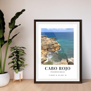 Può includere: Stampa incorniciata con un paesaggio costiero di Cabo Rojo, Porto Rico. L'immagine mostra una costa rocciosa con acque turchesi sotto un cielo blu. La stampa include il nome del luogo e le coordinate.