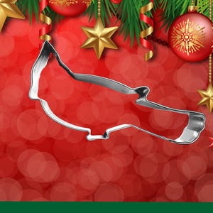 May include: A silver metal cookie cutter shaped like a cardinal bird. The cutter is on a red background with a blurred bokeh effect.