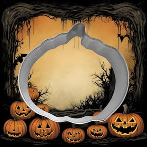 May include: A silver pumpkin-shaped cookie cutter against a Halloween-themed background. The background features orange jack-o'-lanterns, a spooky forest, and a full moon. The cookie cutter is made of metal and is in the foreground.