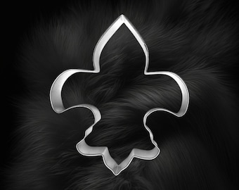 May include: A silver metal cookie cutter in the shape of a fleur-de-lis.