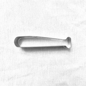 May include: A silver-colored baseball bat-shaped cookie cutter. The cutter is made of metal and has a simple, clean design. The handle is cylindrical, and the barrel is rounded. The cutter is designed for making cookies or other baked goods.