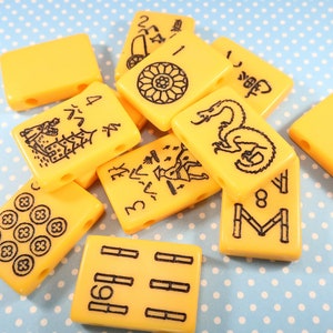 May include: A set of ten yellow mahjong tiles with black Chinese characters and symbols. The tiles are arranged in a random pattern on a blue and white polka dot background.