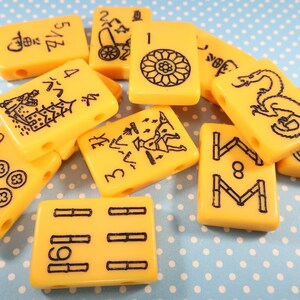 May include: A collection of yellow mahjong tiles with black markings. The tiles feature various symbols and numbers, including a dragon, bamboo, and circles.