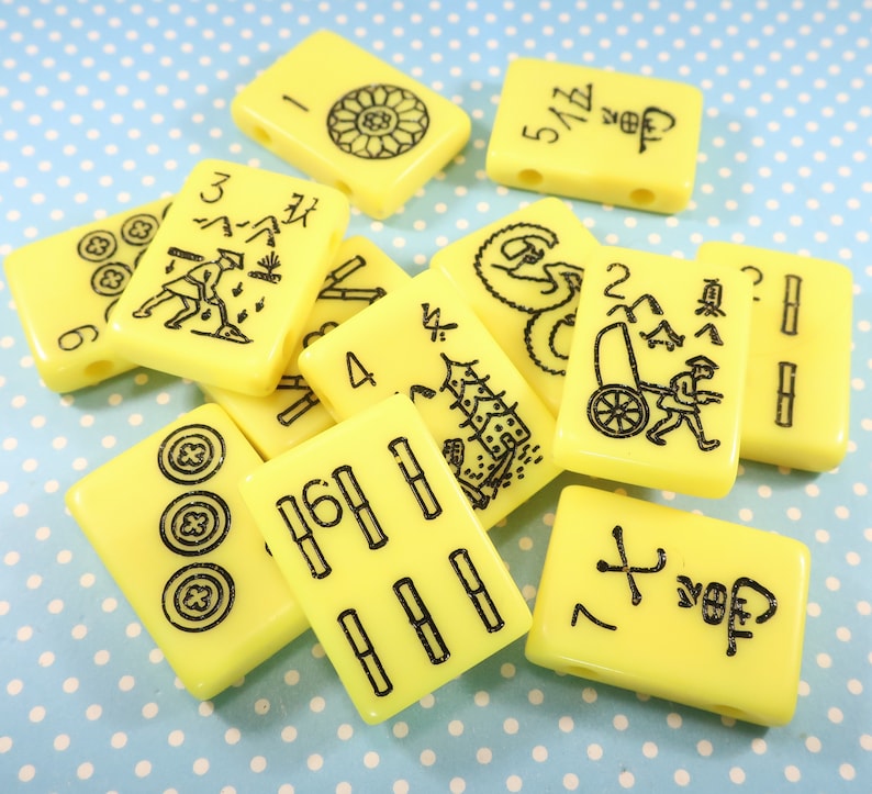 May include: A set of yellow mahjong tiles with black markings. The tiles feature numbers, symbols, and characters. The tiles are arranged in a random pattern.