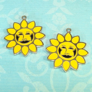 Può includere: Due ciondoli a forma di girasole giallo con facce sorridenti e dettagli neri. I ciondoli hanno un bordo color argento e un piccolo anello nella parte superiore per il fissaggio a gioielli o altri lavori artigianali. I petali di girasole sono giallo brillante.