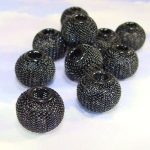 Könnte beinhalten: Eine Gruppe von zehn schwarzen Mesh-Perlen mit einem Loch in der Mitte jeder Perle. Die Perlen sind in Pyramidenform angeordnet.