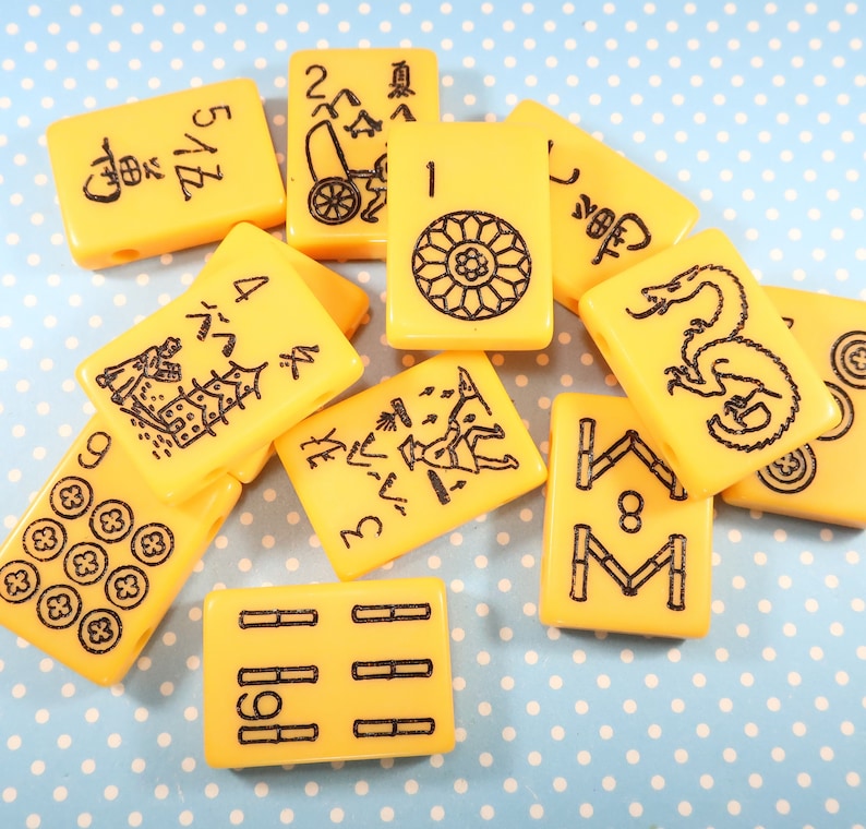 May include: A set of yellow mahjong tiles with black Chinese characters and symbols. The tiles feature numbers, characters, and symbols.