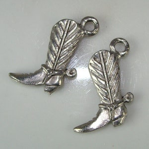 May include: Two silver cowboy boot charms with a feather design and a spur on the heel.