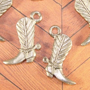 May include: Silver tone metal cowboy boot charms with a feather design and a spur. The charms have a loop at the top for attaching to a necklace, bracelet, or other jewelry.