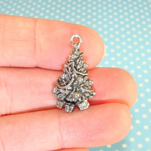 Puede incluir: Encanto de plata en forma de &aacute;rbol de Navidad con adornos y lazos.